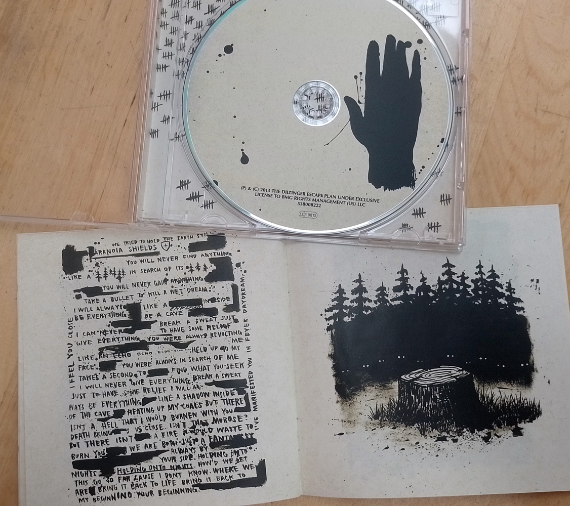 CD copy of One of Us is the Killer by The Dillinger Escape Plan, jewel case and booklet opened up to show the CD and additional artowkr